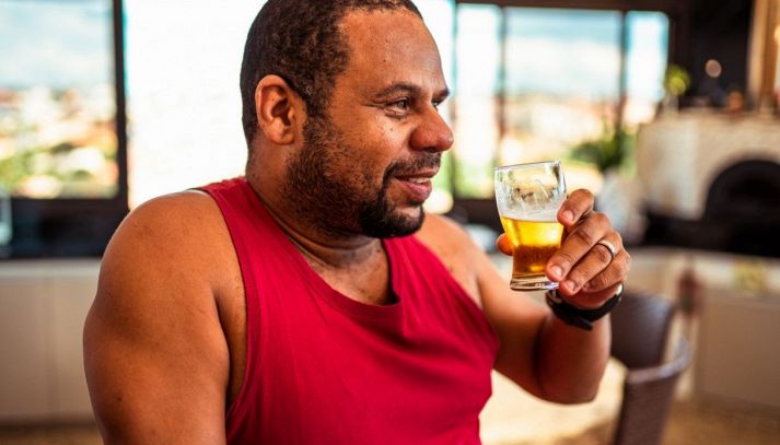 Uomo in canottiera rossa beve una birra in un ristorante