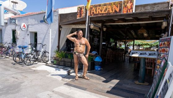 Un uomo seminudo posa fuori da un ristorante di mare 
