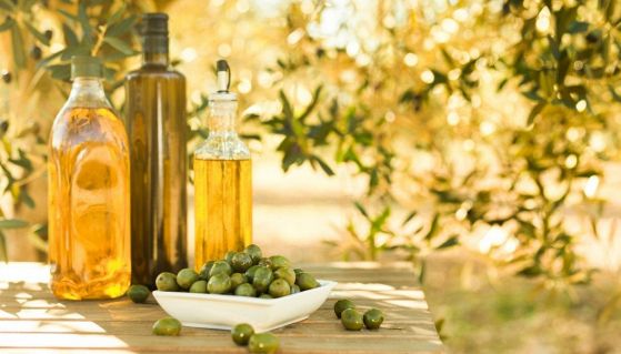 Bottiglie di olio e olive mature su un tavolo in un uliveto