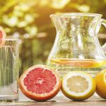Agrumi in primo piano con caraffa di succo alle spalle