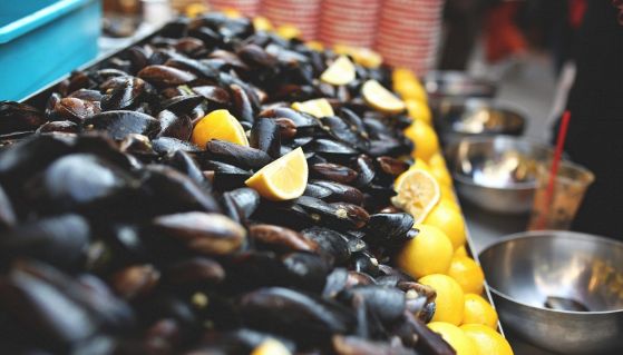 Cozze fresche in vendita sul bancone con limoni