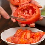 Mani femminili svuotano pomodori dalla polpa