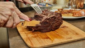 Mani femminili affettano un pezzo di carne cotta