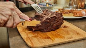 Mani femminili affettano un pezzo di carne cotta