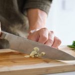 Tritare l'aglio al coltello sul tagliere