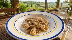 Piatto di gnocchi al limone con campagna sullo sfondo