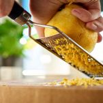 Mani grattugiano il limone con grattugia manuale