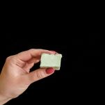 Mano di donna che regge cubetto di gelato al pistacchio ghiacciato