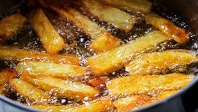 Delle patatine friggono nell'olio bollente in padella