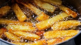 Delle patatine friggono nell'olio bollente in padella
