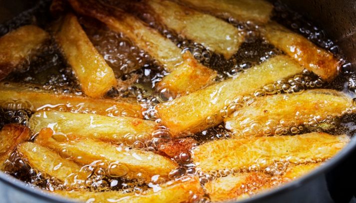 Delle patatine friggono nell'olio bollente in padella