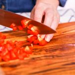 Tagliere con mani che affettano peperone rosso