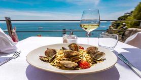 Piatto di linguine allo scoglio con mare sullo sfondo