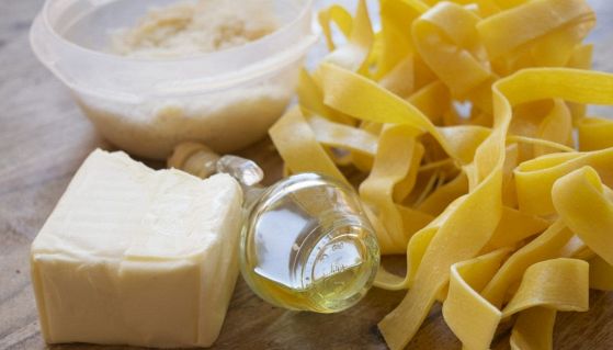 Un panetto di burro, olio d'oliva, parmigiano grattugiato e tagliatelle