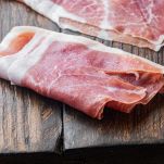 Tavolo di legno con fette di prosciutto crudo
