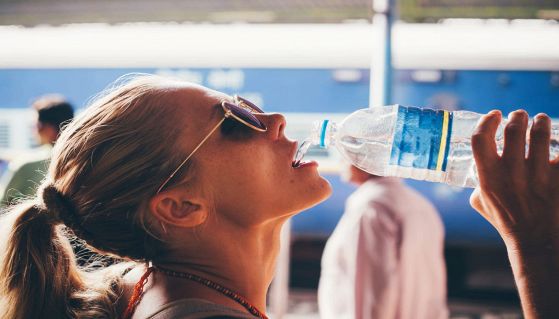 Ragazza accaldata beve acqua in bottiglia