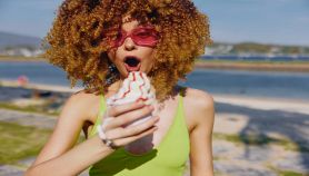 Ragazza tiene un gelato sciolto con mare sullo sfondo