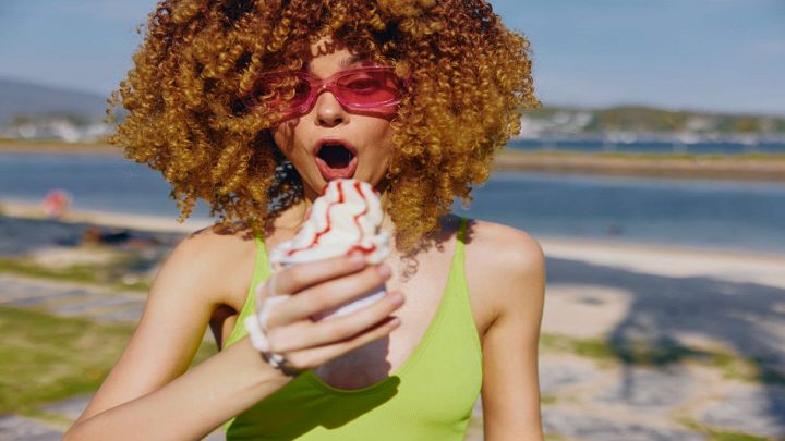 Ragazza tiene un gelato sciolto con mare sullo sfondo