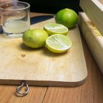 Tagliere con lime tagliato e bicchiere con succo