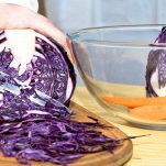 Tagliere con cavolo viola che viene affettato