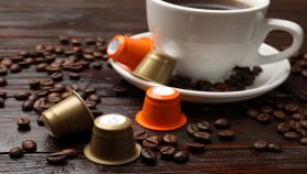 Tavolo con tazzina di caffè, capsule e chicchi