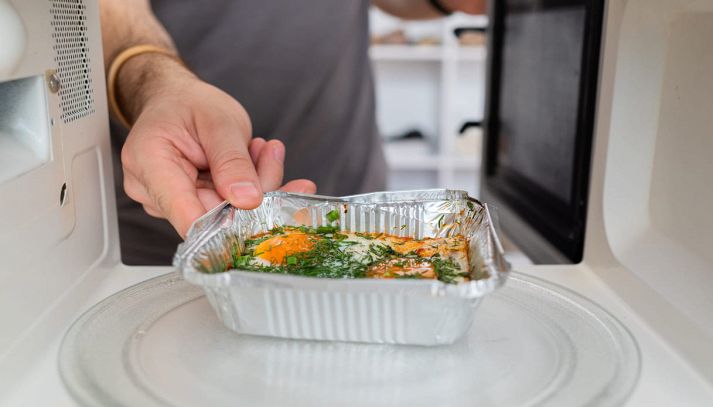 Cibo già pronto messo nel microonde da un uomo