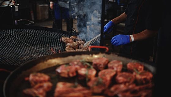 Delle bistecche di carne cuociono su una griglia ardente nel patio interno di una steakhouse