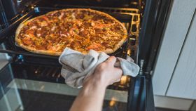 Mani femminili controllano la pizza nel forno