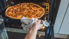 Mani femminili controllano la pizza nel forno