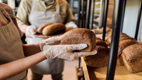 Mani guantate reggono il pane nel panificio