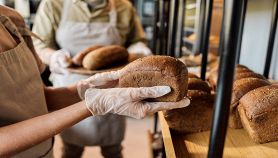 Mani guantate reggono il pane nel panificio