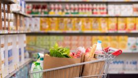 Un carello della spesa pieno di prodotti in una corsia di un supermarket