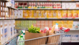 Un carello della spesa pieno di prodotti in una corsia di un supermarket