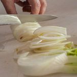 Tagliere con finocchio che viene affettato