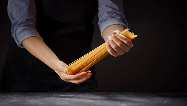 Donna regge spaghetti crudi con le mani