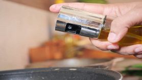 Oliera spray nella mano di una persona sulla pentola