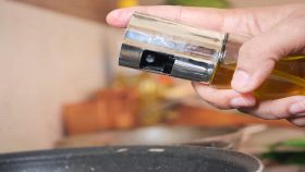 Oliera spray nella mano di una persona sulla pentola