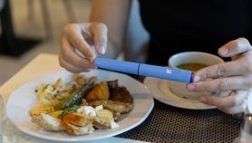 Una donna mangia porzioni ridotte in un ristorante mentre impugna una siringa portatile di Ozempic