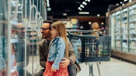 Un padre guarda incantato degli snack e gelati per bambini insieme alla figlia al supermercato