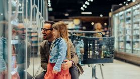 Un padre guarda incantato degli snack e gelati per bambini insieme alla figlia al supermercato