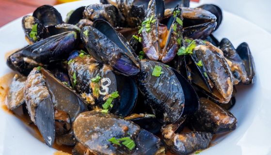 Un piatto di cozze con sughetto e prezzemolo