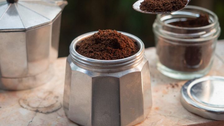 Mano mette il caffè nella moka con il cucchiaio