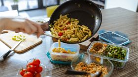 Donna spadella dei fusilli con verdure e prepara delle porzioni settimanali per la schiscetta al lavoro