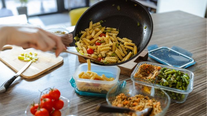 Donna spadella dei fusilli con verdure e prepara delle porzioni settimanali per la schiscetta al lavoro
