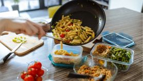 Donna spadella dei fusilli con verdure e prepara delle porzioni settimanali per la schiscetta al lavoro