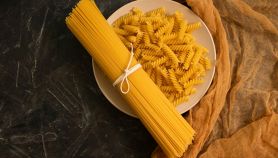 Un mazzo di spaghetti legati con un nastro su un piatto di fusilli pronti da cuocere