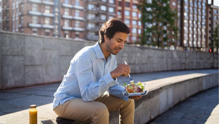 Uomo mangia dalla sua schiscetta all'aperto e in pausa pranzo 