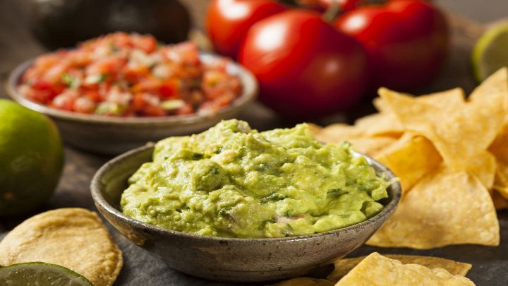 Guacamole nella ciotolina con altri ingredienti sullo sfondo
