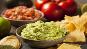 Guacamole nella ciotolina con altri ingredienti sullo sfondo