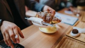 Cliente con un croissant ripieno di gelato si siede al tavolino di un bar
